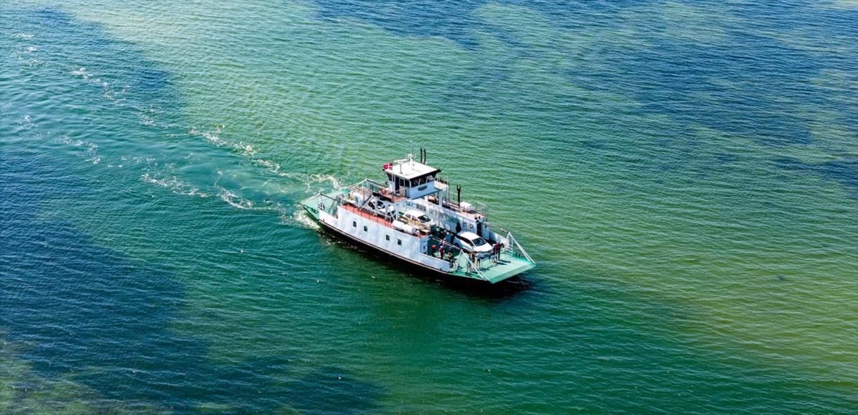 Columbus færgen sejler på åbent, grønt hav med biler og passagerer ombord set fra oven.